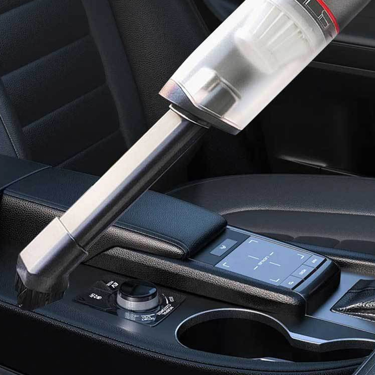 Ein Handstaubsauger reinigt einen Auto Innenraum. Der Staubsauger ist silber und schwarz, mit Bürstenaufsatz. Schwarze Ledersitze.