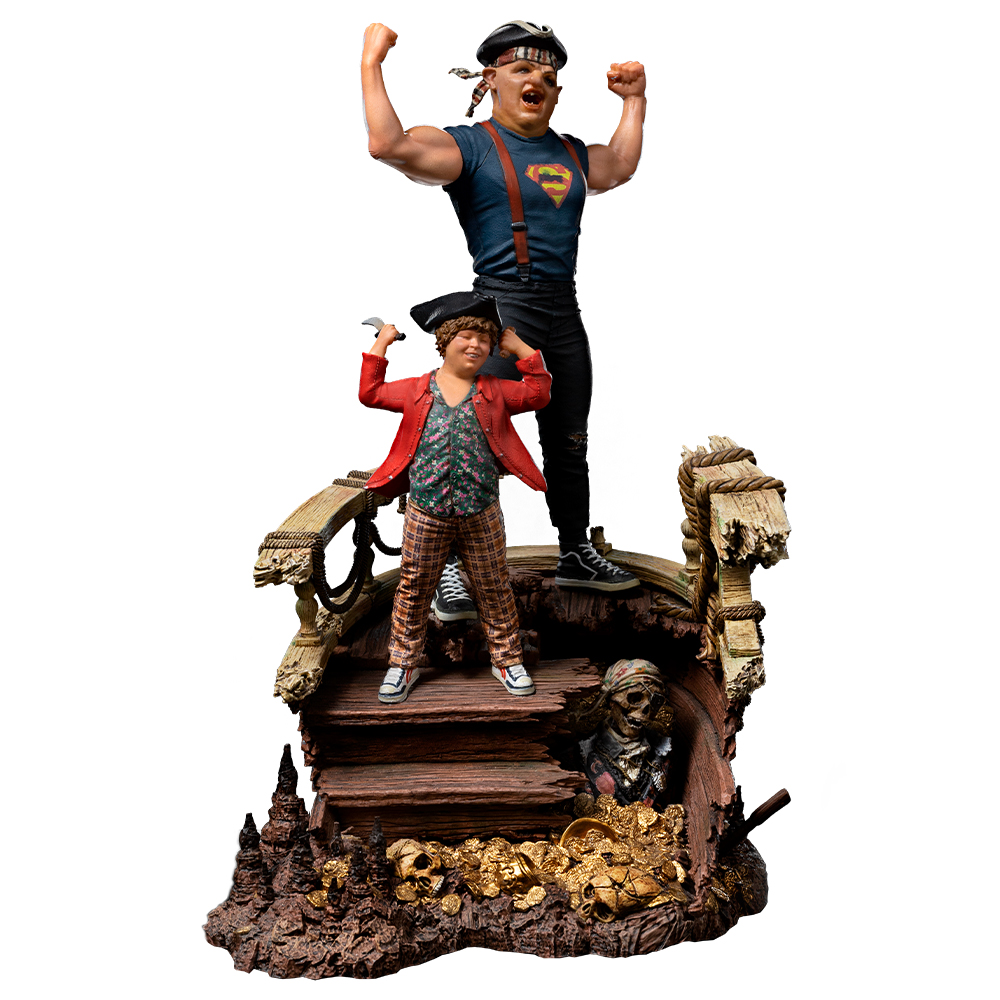 Statue von zwei Figuren auf einer Holzkonstruktion. Einer hebt die Arme, der andere hält einen Haken. Im Hintergrund ein Totenkopf mit Bandana.