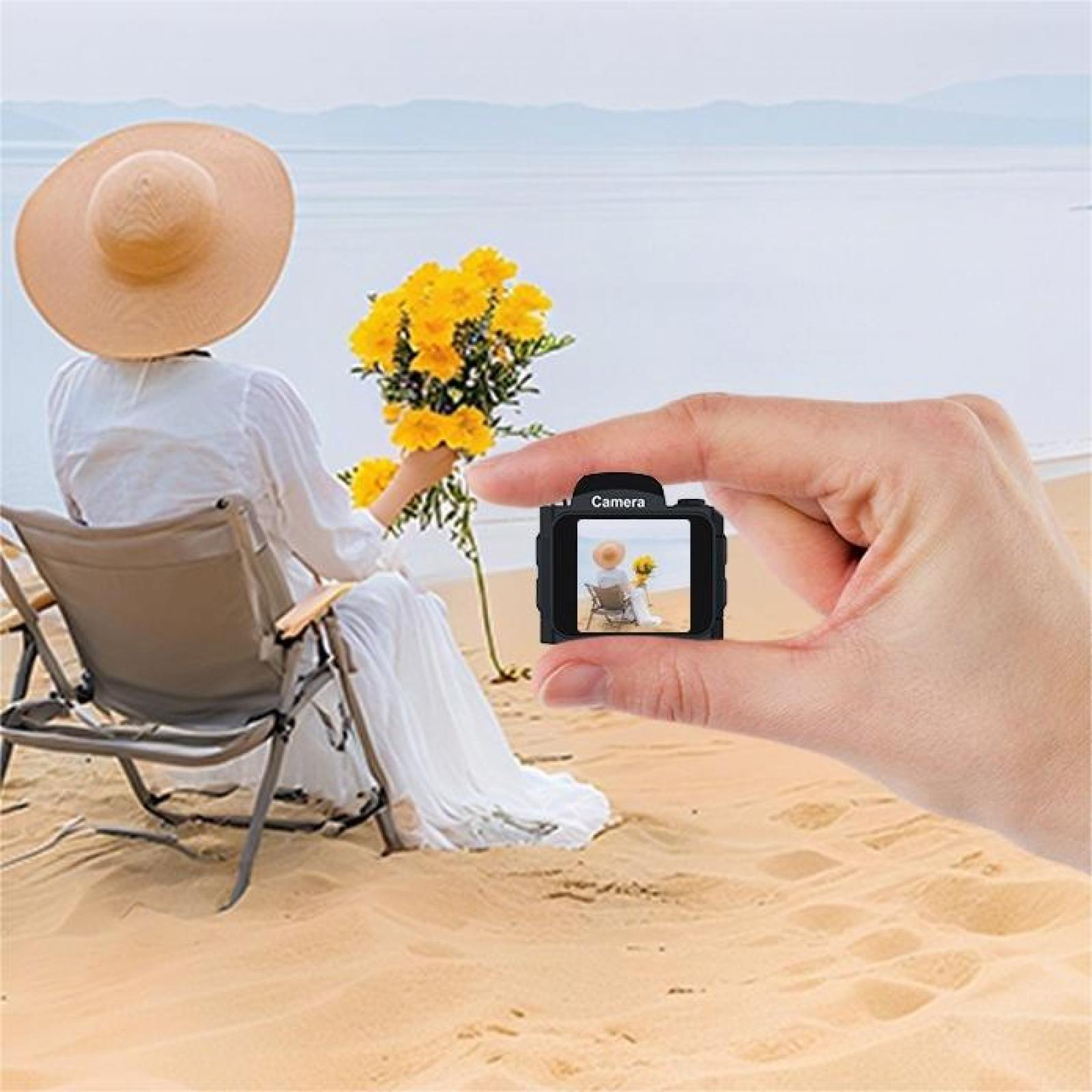 Eine Person in weißem Kleid und Hut sitzt auf einem Strandstuhl und hält gelbe Blumen. Eine Kamera zeigt dieselbe Szene.