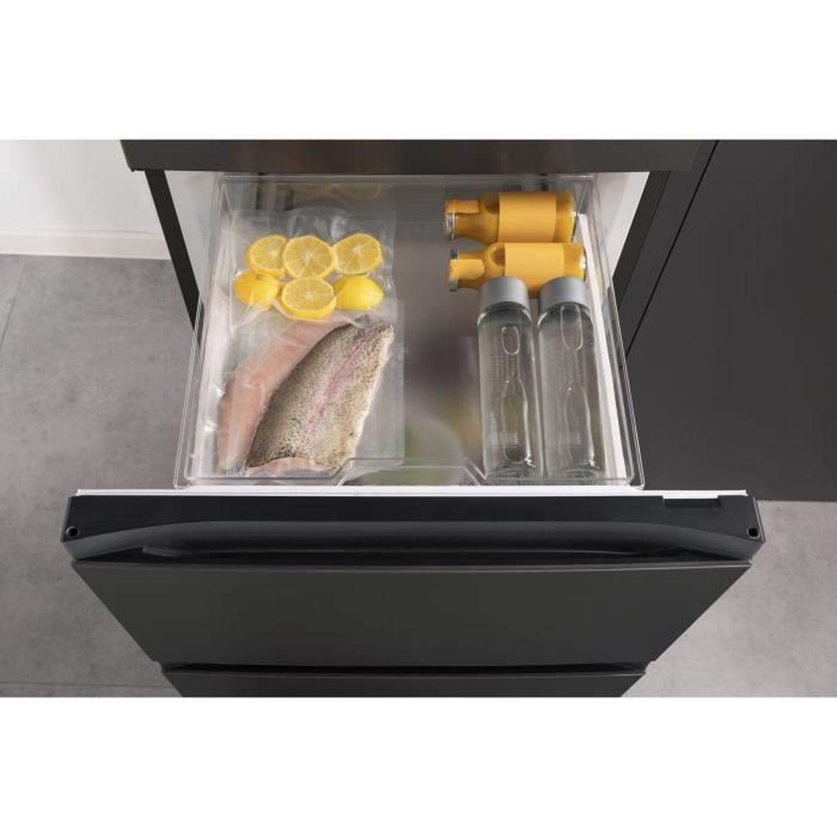 Kühlschublade mit Zitronen, Fisch und Flaschen. Gelbe Flaschen sind rechts. Die Schublade ist geöffnet und zeigt den Inhalt.