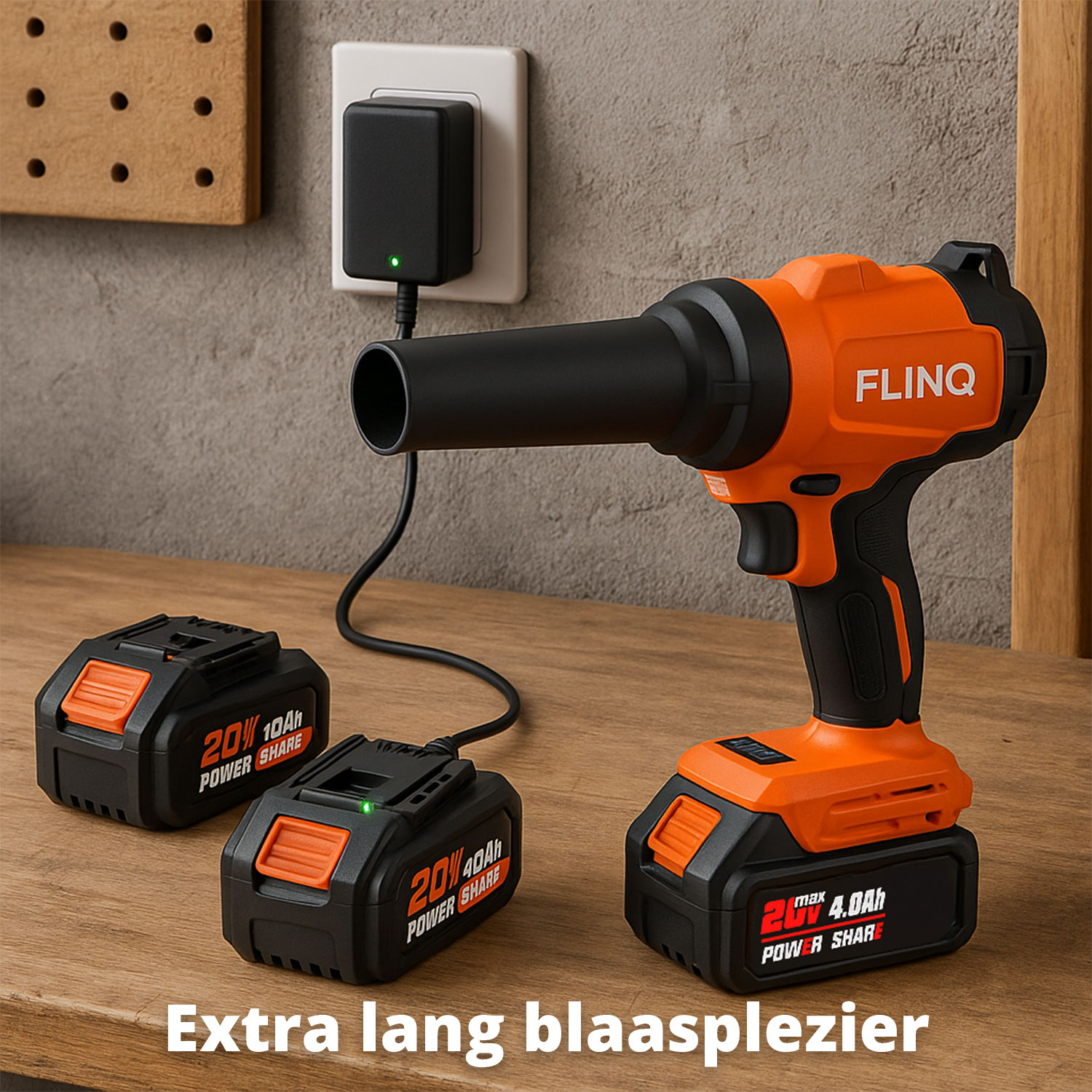 An orange and black FLINQ leaf blower sits on a wooden table with two charging batteries. A charger is plugged into a wall outlet.