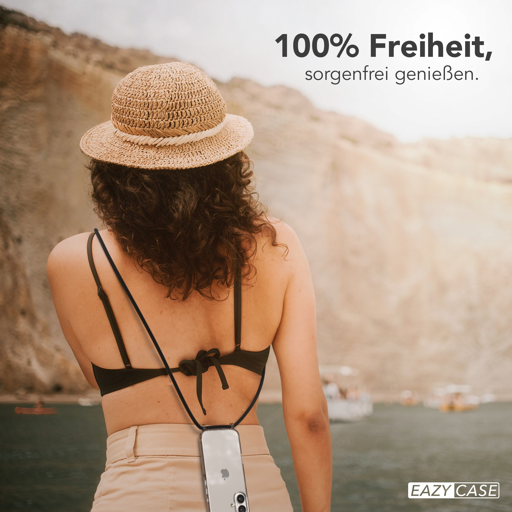 Frau mit Hut, schwarzem Oberteil und Handyhülle, weg von der Kamera. Der Hintergrund zeigt Berge und Wasser.