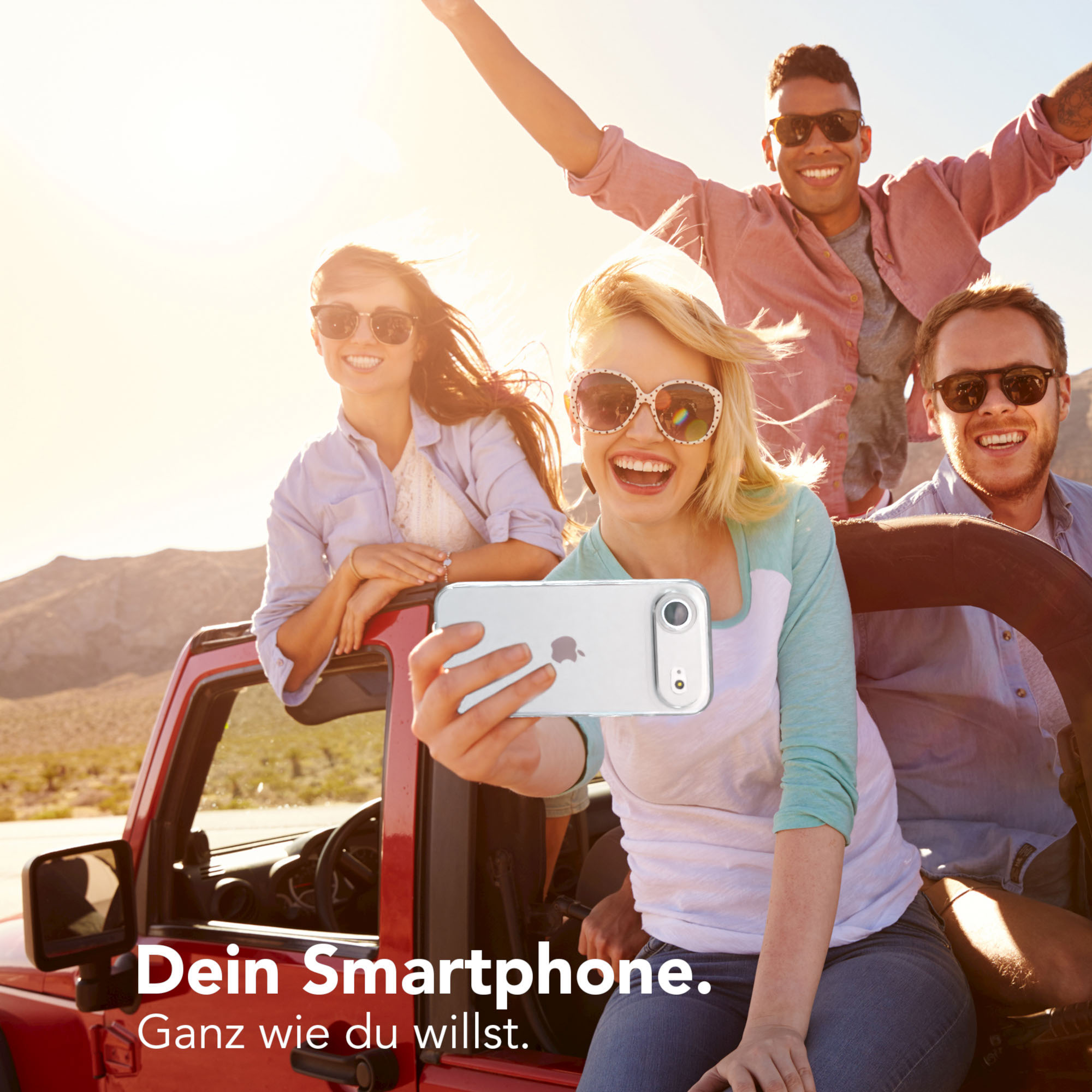Freunde machen ein Selfie in einem roten Auto. Sie lächeln und genießen den sonnigen Tag.