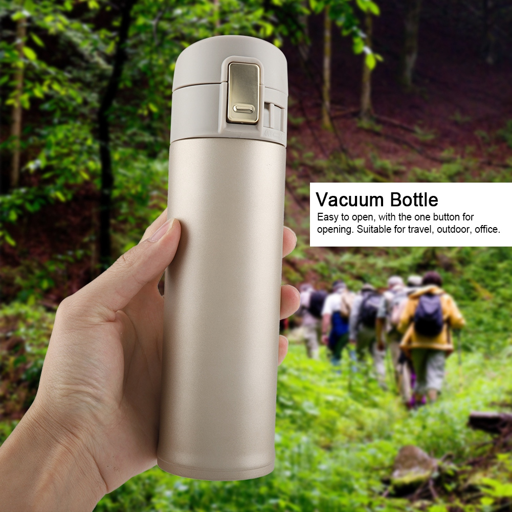 Eine Hand hält eine beige Vakuumflasche. Im Hintergrund gehen Menschen auf einem grünen Pfad im Wald.