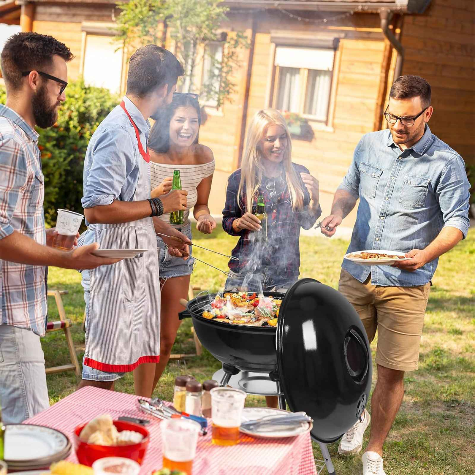 Gruppe von Leuten beim Grillen. Ein schwarzer Grill ist geöffnet und kocht Essen. Leute lächeln und halten Getränke. Ein Tisch ist gedeckt.