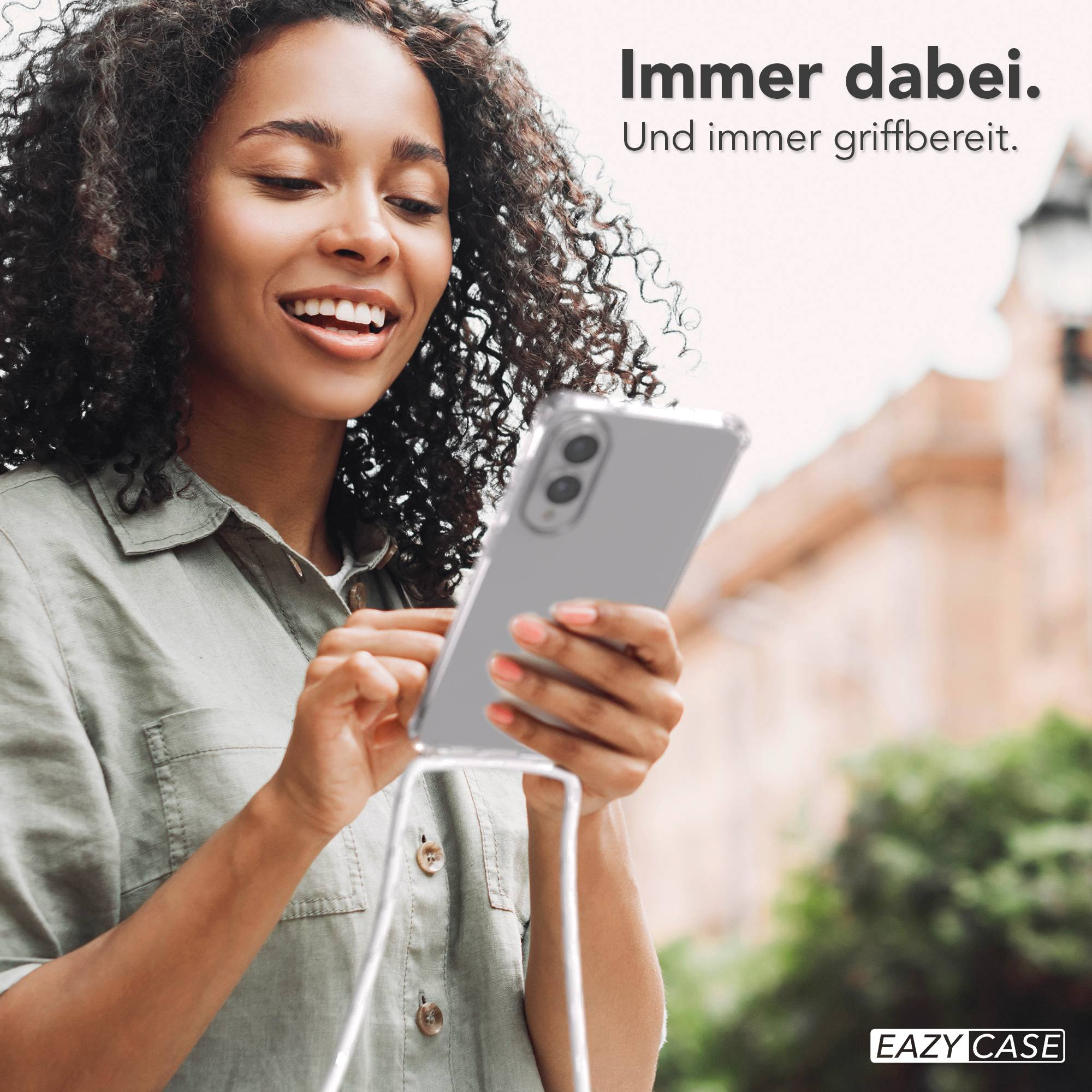Eine Frau lächelt, während sie ein Telefon in einer transparenten Hülle hält. Der Text sagt: 'Immer dabei'.