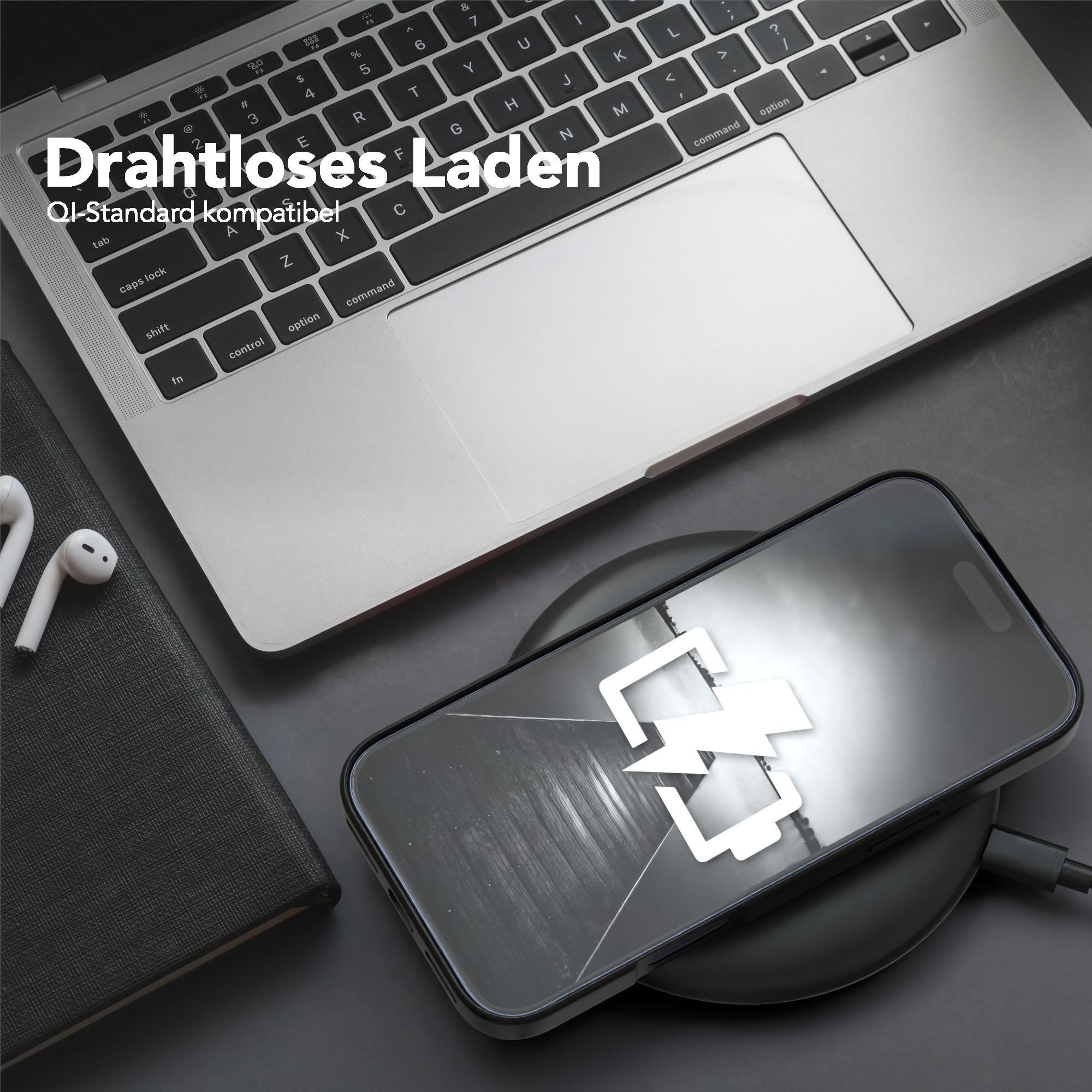Laptop, Telefon, das auf einem kabellosen Ladegerät geladen wird. Kopfhörer und Notizbuch.