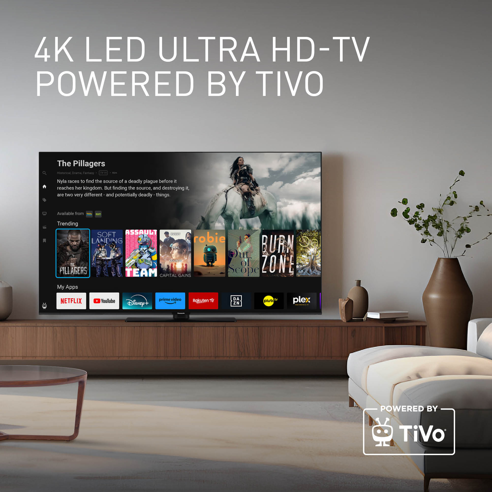 Telewizor wyświetla film. Poniżej znajdują się ikony aplikacji. W pokoju znajduje się sofa i drewniana szafka.