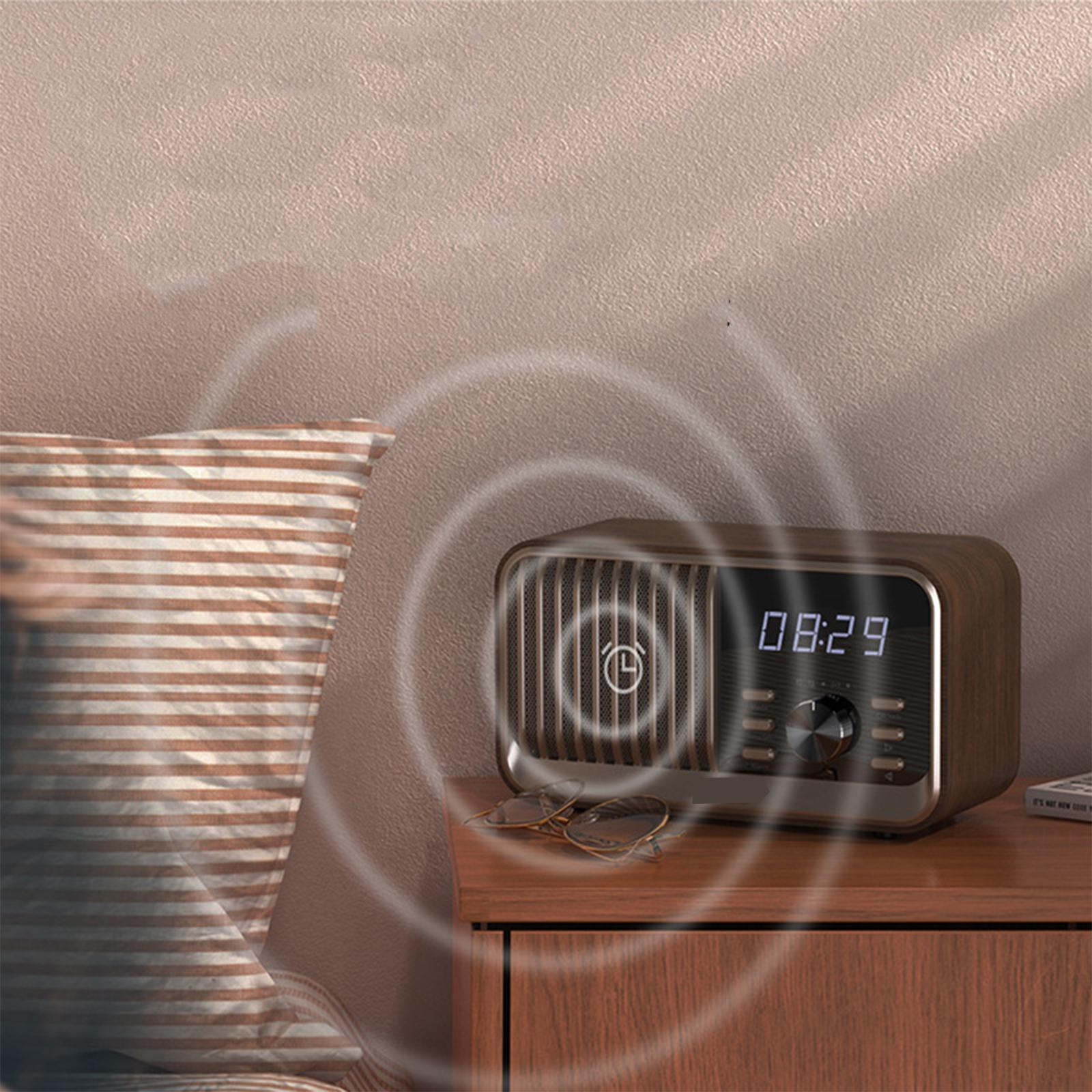 Holz-Radiowecker auf einem Nachttisch. Eine Brille liegt daneben. Links ein gestreiftes Kissen. Die Uhrzeit ist 08:29.