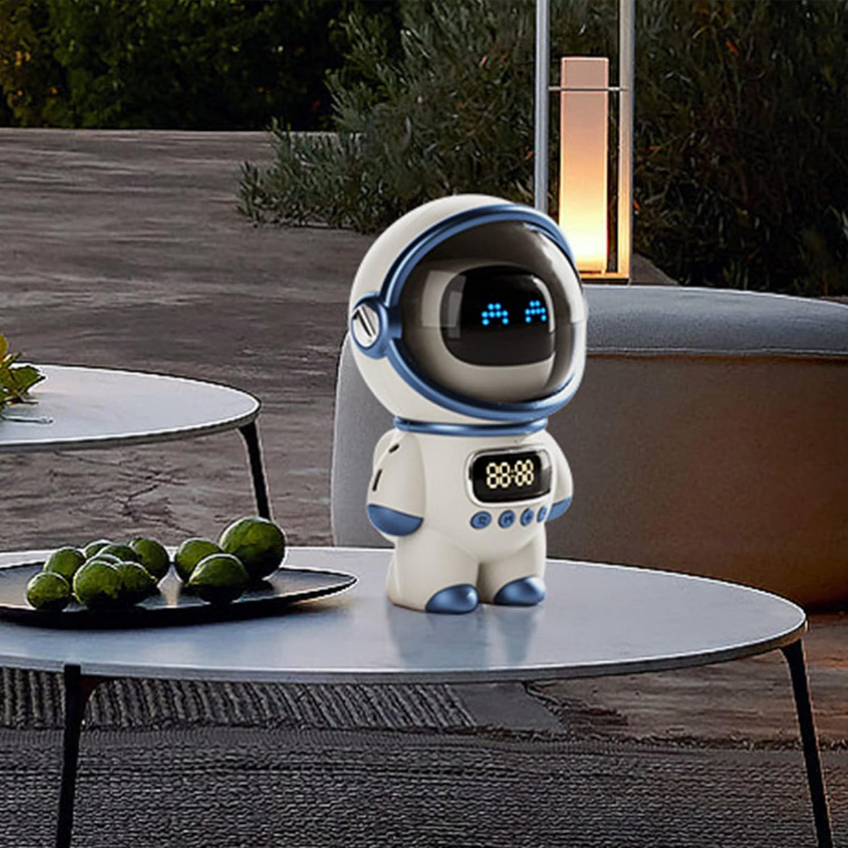 Ein Astronautenroboter sitzt auf einem Tisch. Er hat ein Bildschirmgesicht und eine Zeitanzeige. Limetten liegen auf einem anderen Tisch in der Nähe.