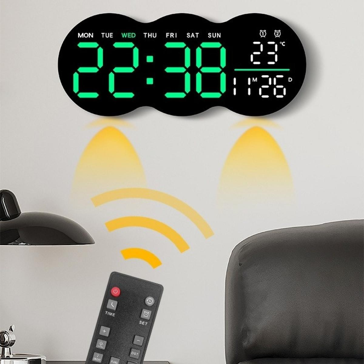 Digitale Uhr mit Anzeige von Zeit und Datum. Eine Fernbedienung ist im Vordergrund. Eine Lampe und ein Stuhl sind ebenfalls im Bild.