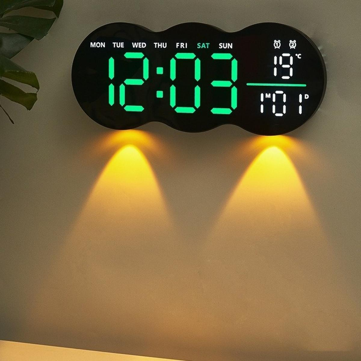 Eine Digitaluhr zeigt 12:03 und 19 Grad an. Sie ist an einer Wand montiert, auf die zwei Scheinwerfer scheinen.