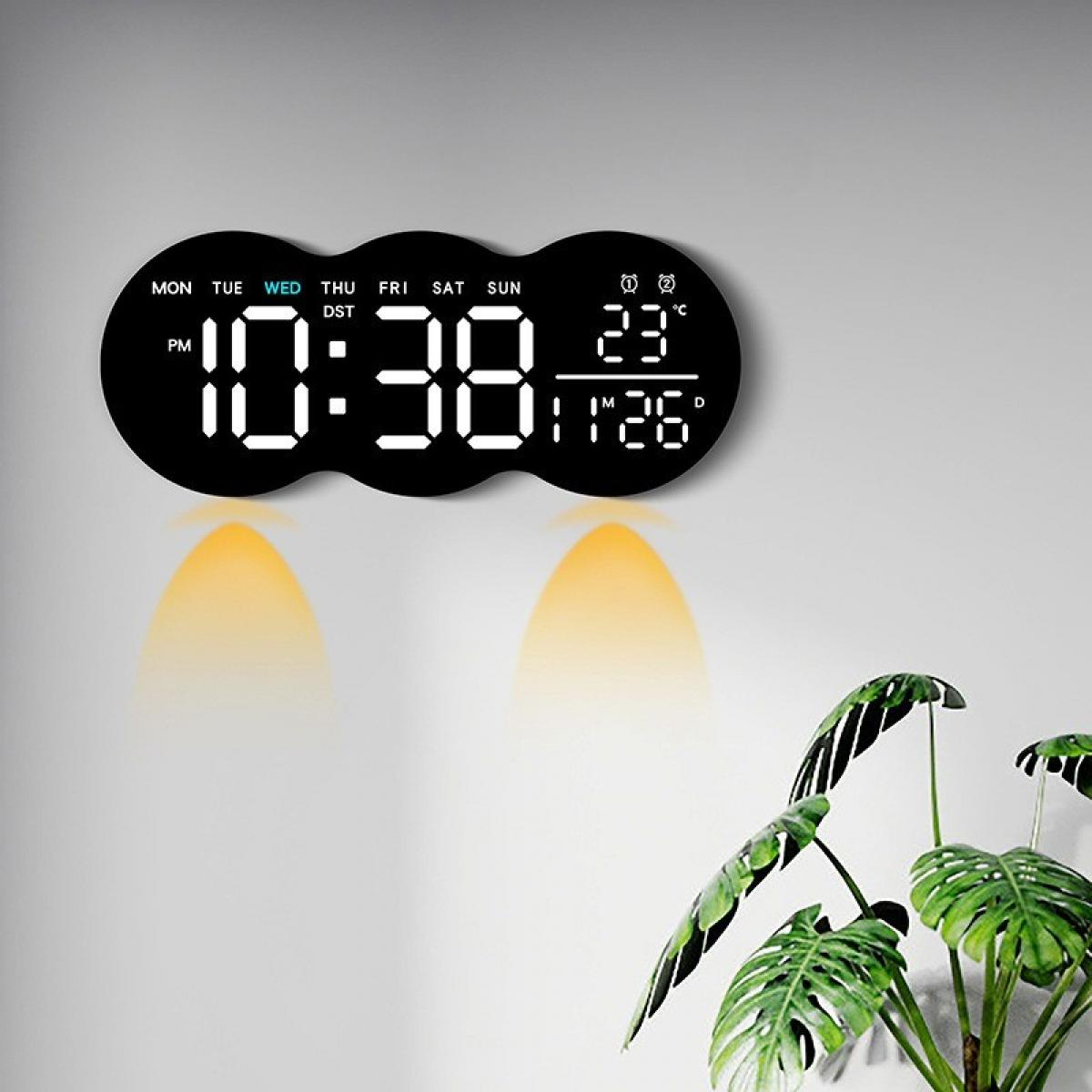 Eine Digitaluhr zeigt die Uhrzeit. Die Uhr befindet sich an einer Wand über einer Pflanze. Die Uhrzeit ist 10:38. Die Temperatur beträgt 23 Grad Celsius.