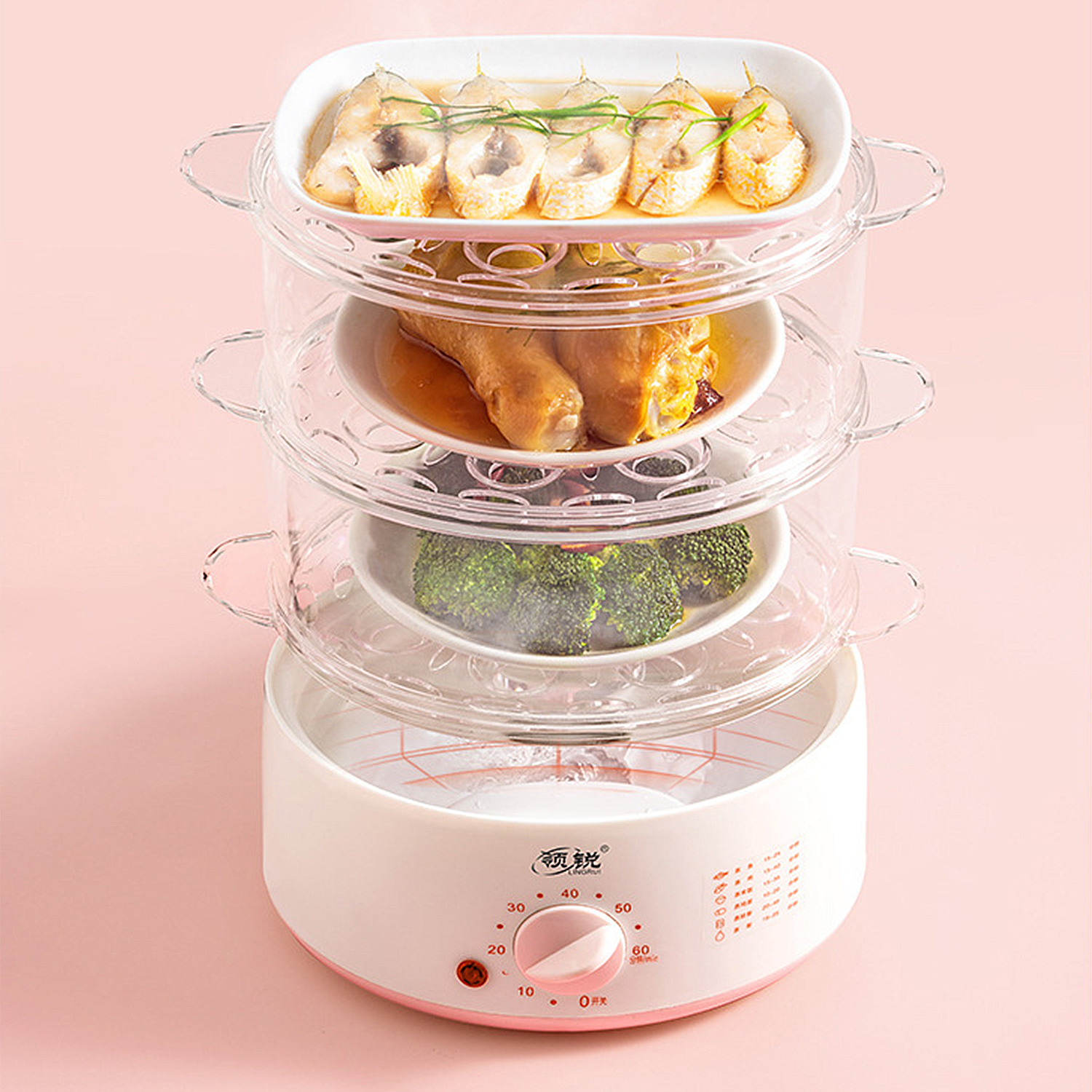 Ein dreistufiger Dampfgarer mit Fisch, Huhn und Brokkoli. Er ist rosa und weiß auf rosa Hintergrund.
