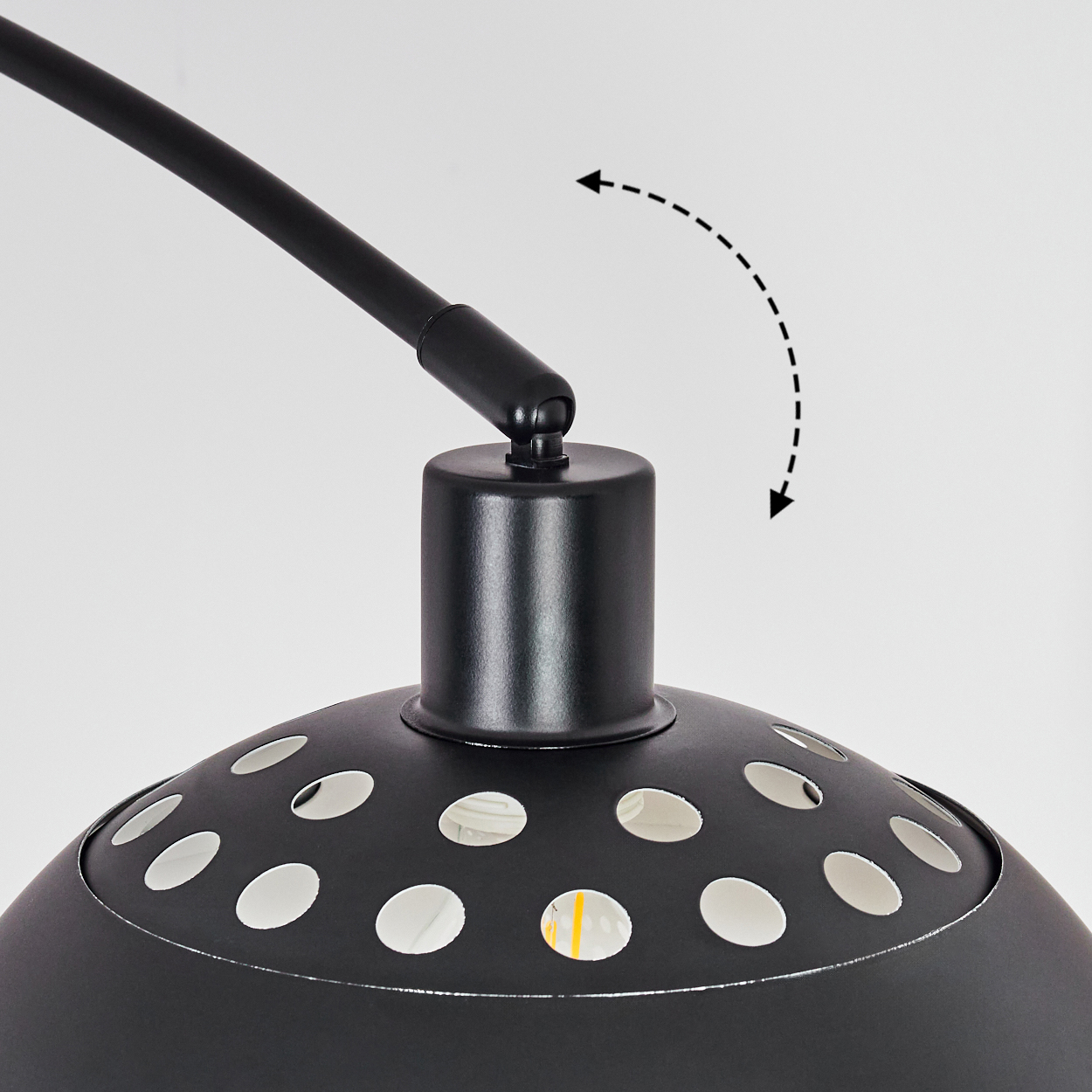 Nahaufnahme einer schwarzen Lampe mit gebogenem Arm, perforiertem Schirm und weißem Hintergrund. Gepunkteter Pfeil zeigt Bewegung an.