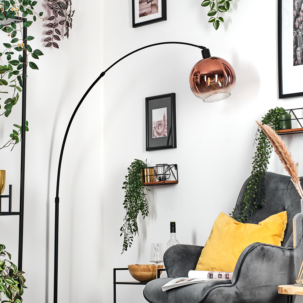 Ein modernes Wohnzimmer mit grauem Sessel und gelbem Kissen, einer Kupferlampe und Pflanzen an der Wand.