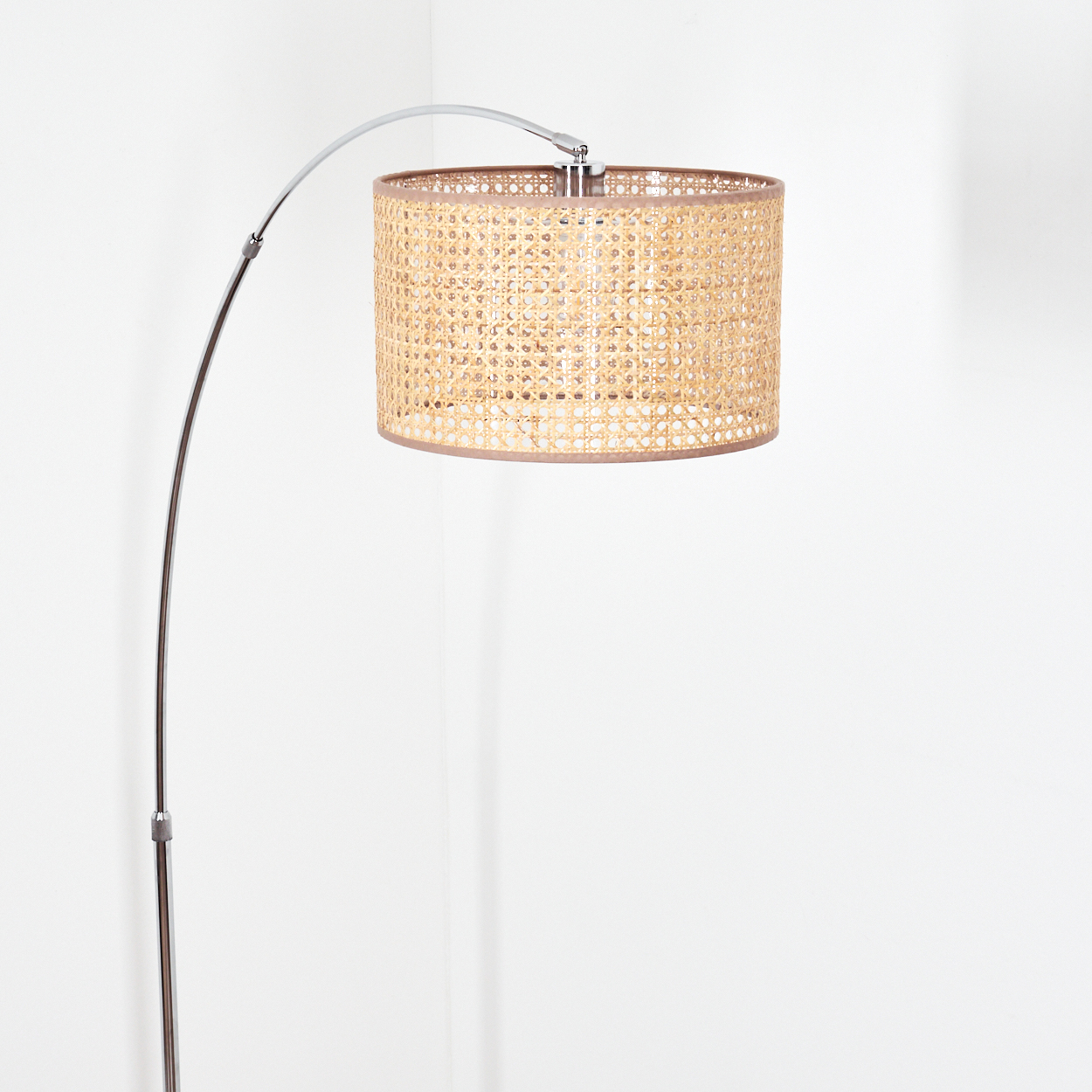 Eine moderne Bogen-Stehlampe mit einem gewebten Lampenschirm. Der Lampenschirm ist zylindrisch, beige und der Fuß ist metallisch. Der Hintergrund ist weiß.