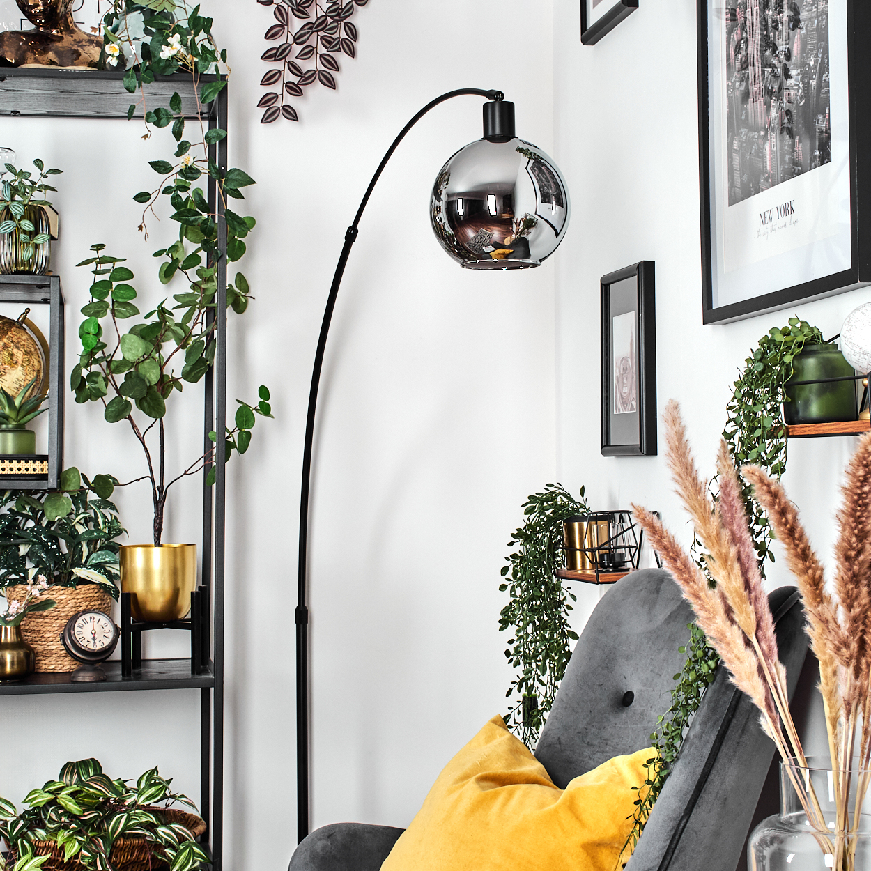 Ein Zimmer mit einer schwarzen Stehlampe, Pflanzen, einem grauen Sessel mit gelbem Kissen und einem New York-Bild.