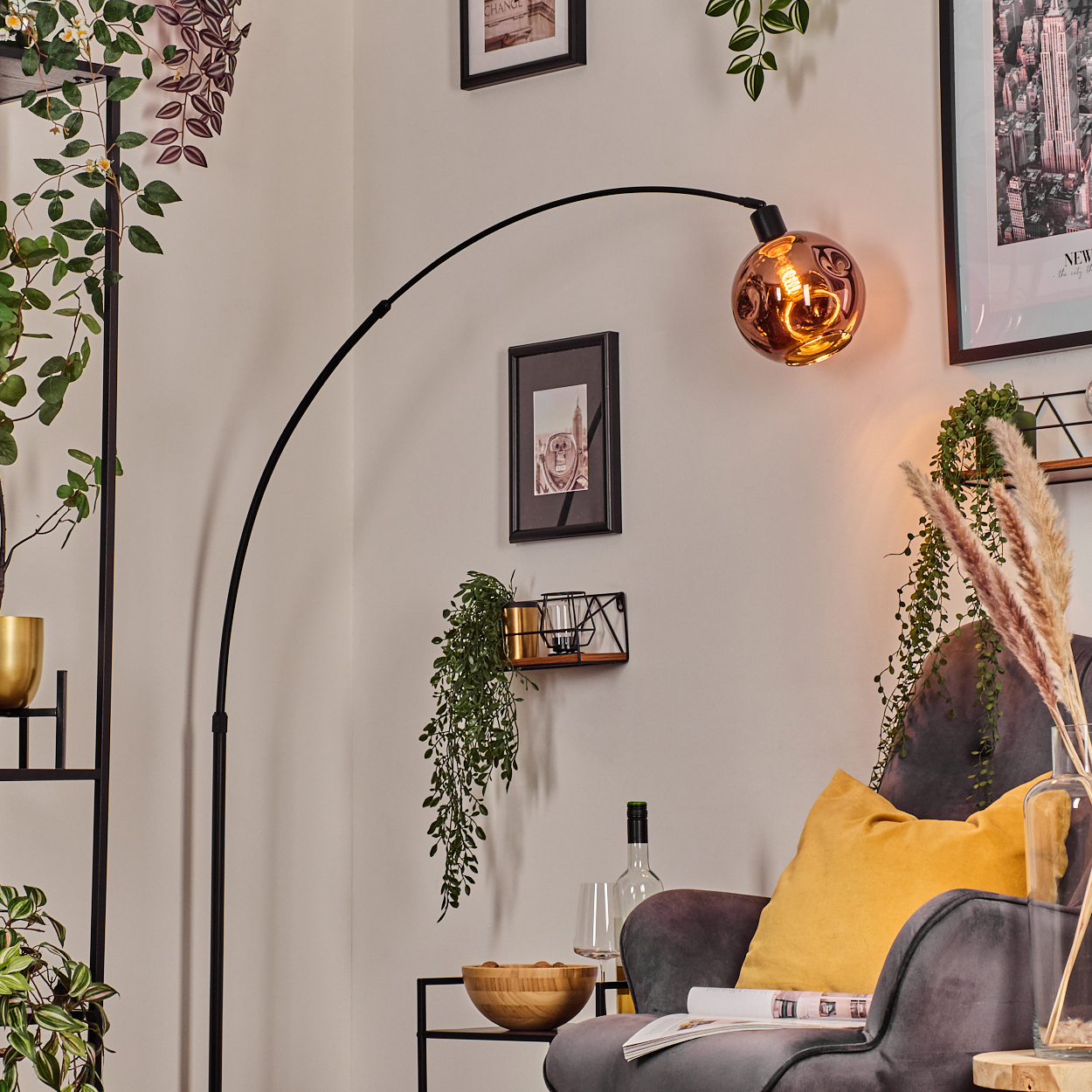 Ein modernes Wohnzimmer mit schwarzer Stehlampe, grauem Sessel, gelbem Kissen und dekorativen Pflanzen.