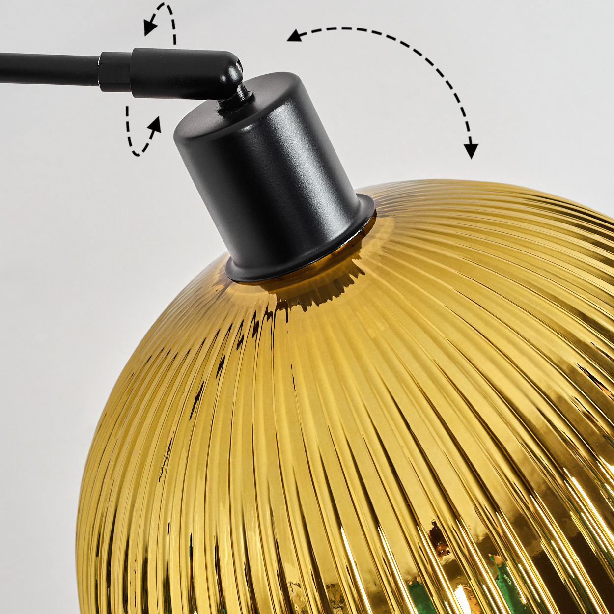 Nahaufnahme einer Lampe. Die Lampe hat einen gelben, gerippten Glasschirm und einen schwarzen Metallarm und -gelenk. Pfeile zeigen die Bewegung an.