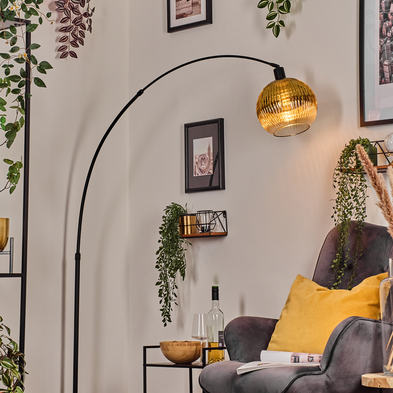 Ein modernes Wohnzimmer mit goldener Lampe, Sessel und Dekorationen. Eine schwarze Lampe wölbt sich über die Szene. Ein gelbes Kissen liegt auf dem Stuhl.