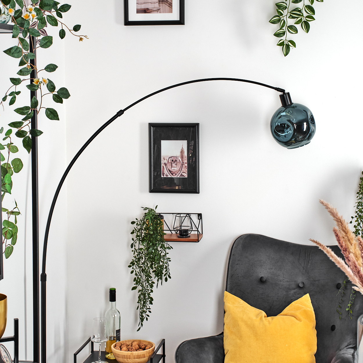 Ein modernes Wohnzimmer mit einer schwarzen Bogenlampe, einem grauen Sessel, einem gelben Kissen und einem Tisch.