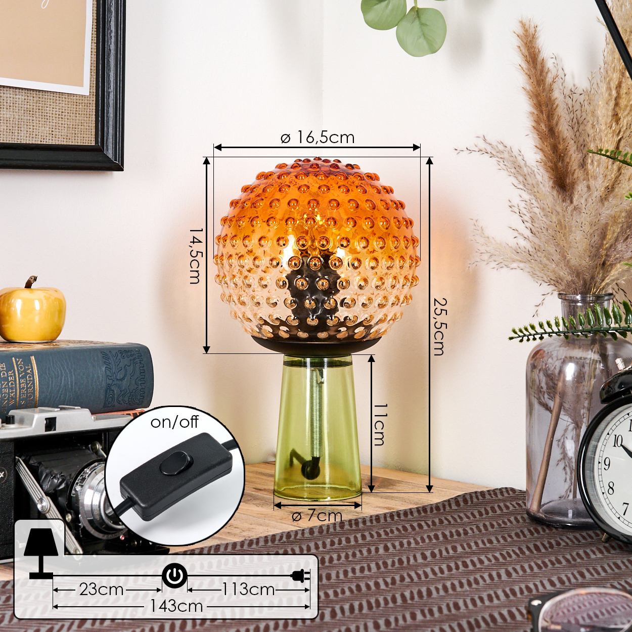 Eine dekorative Lampe mit Glasschirm und grünem Sockel. Sie steht auf einer Holzoberfläche mit anderen Dekorationselementen und Maßen.