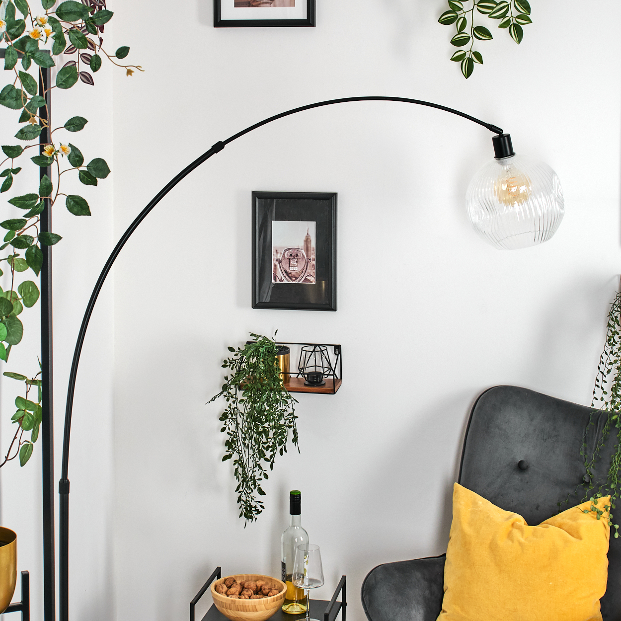 Ein modernes Wohnzimmer mit einer schwarzen Stehlampe, einem grauen Sessel mit gelbem Kissen und einem kleinen Tisch.