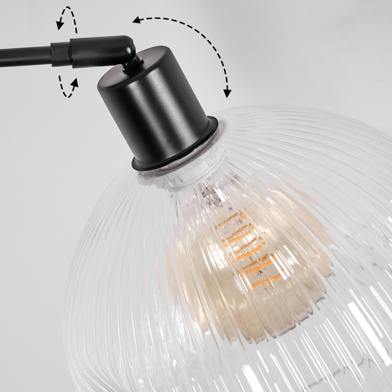 Nahaufnahme einer schwarzen Lampe mit einem klaren, geriffelten Glasschirm. Im Inneren befindet sich eine Glühbirne. Pfeile zeigen die verstellbaren Funktionen.