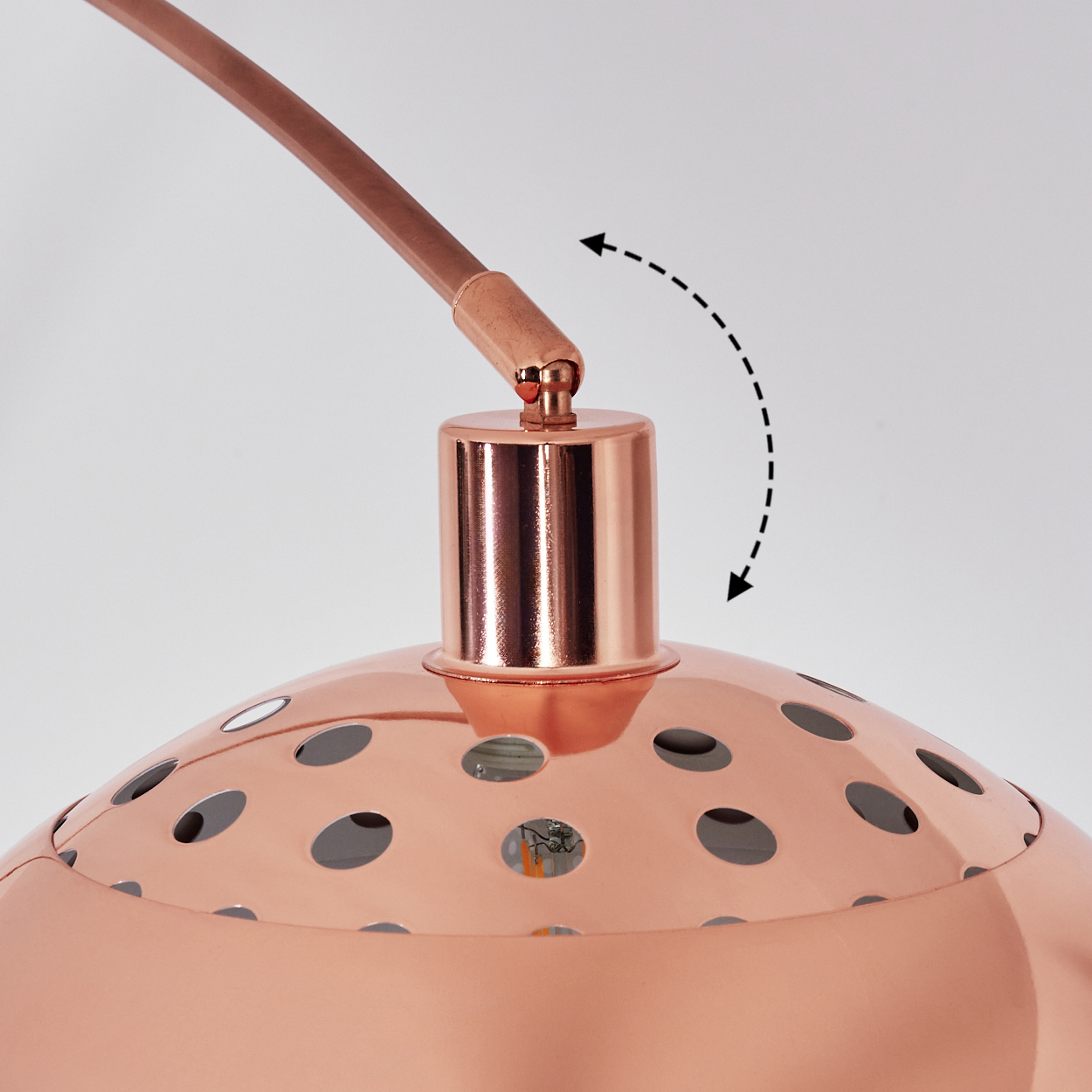 Eine kupferfarbene Lampe mit perforiertem Schirm. Die Lampe hat einen gebogenen Arm und einen zylindrischen Sockel mit verstellbarem Gelenk.