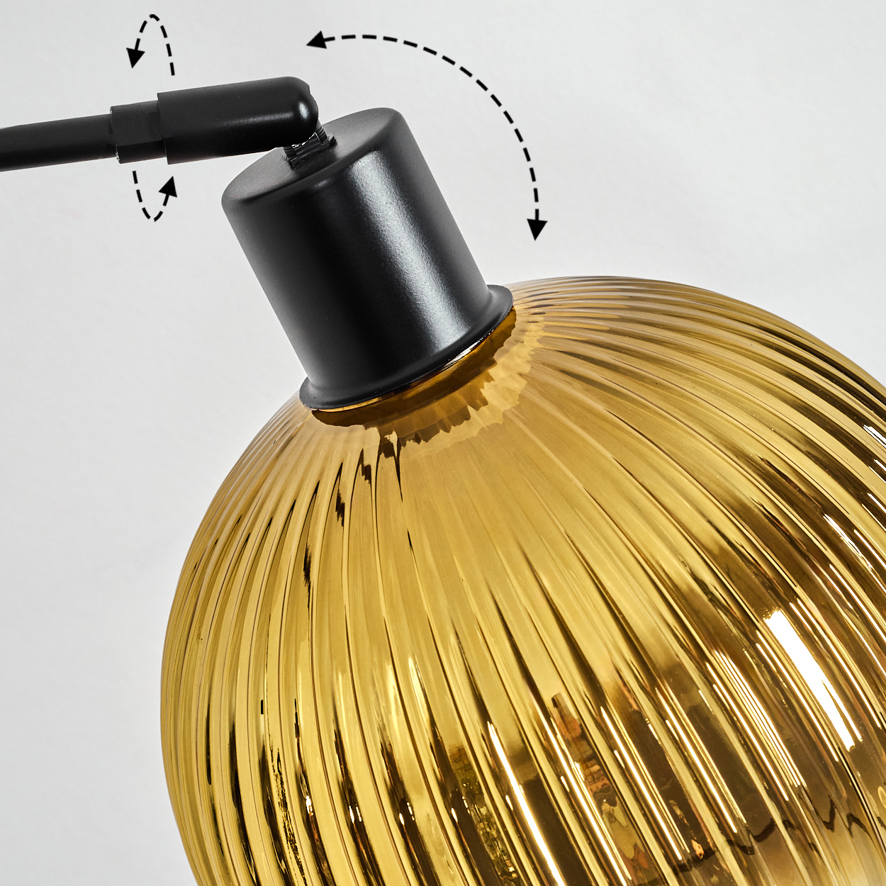 Nahaufnahme einer Lampe. Die Lampe hat einen schwarzen Arm und einen goldenen, gerippten Glasschirm. Pfeile zeigen die Verstellrichtungen an.