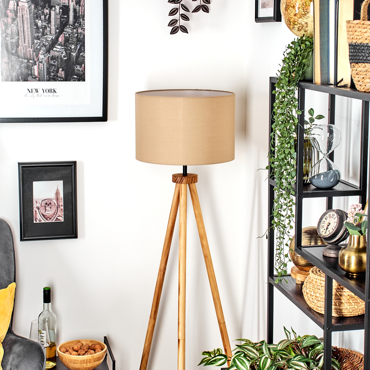 Ein Raum mit einer Holzlampe, einem schwarzen Regal mit Dekorationen, Bildern an der Wand und Pflanzen im Topf.