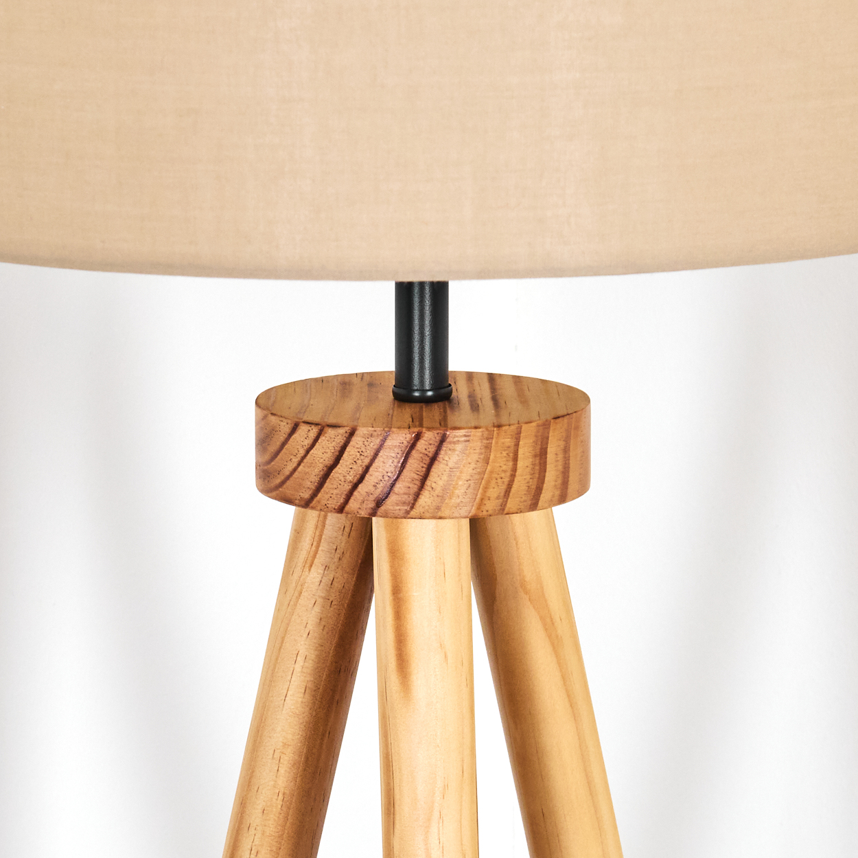 Nahaufnahme einer Lampe. Die Lampe hat einen beigen Lampenschirm, ein Holzstativ und eine schwarze Verbindungsstange.