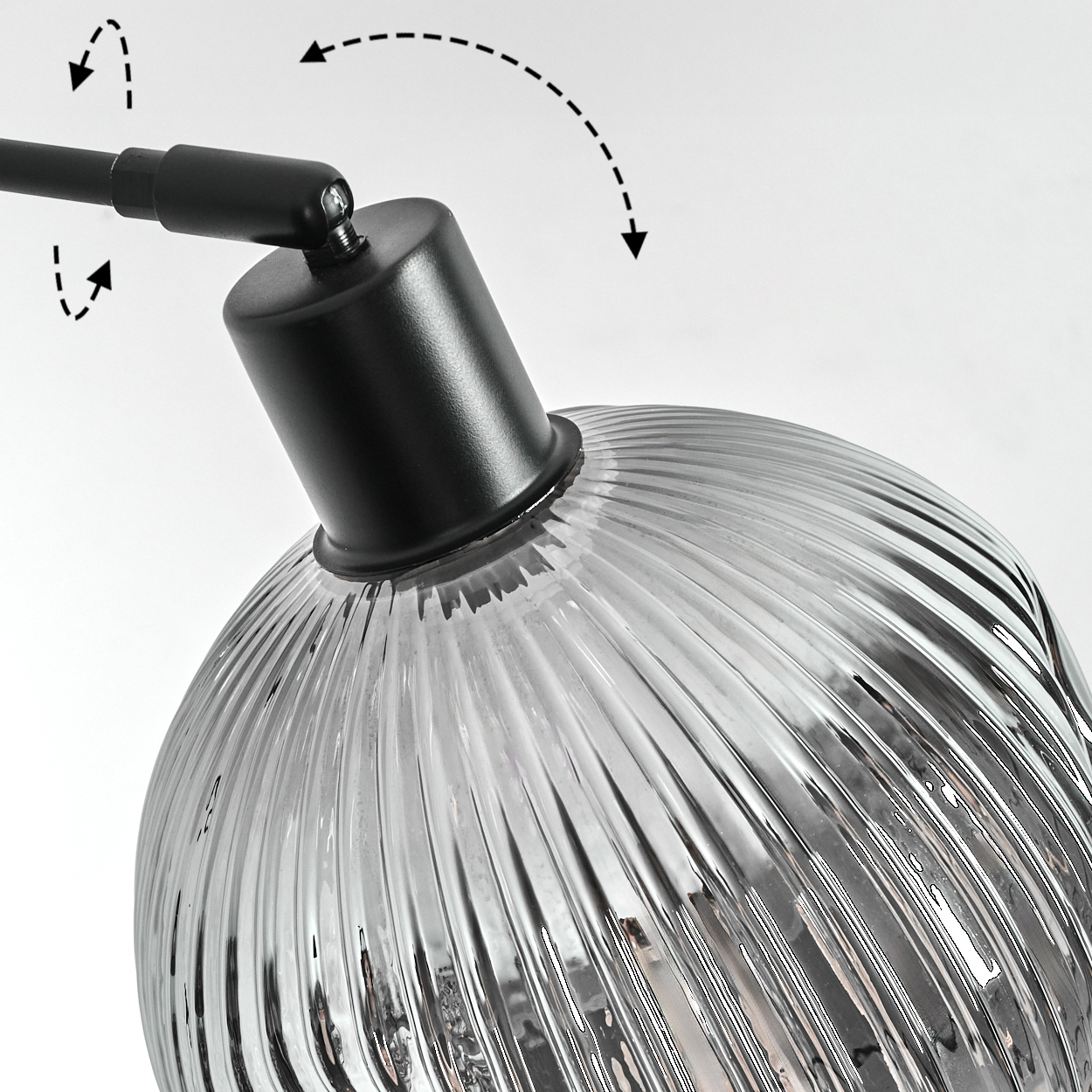 Nahaufnahme einer schwarzen Lampe mit klarem, geripptem Glasschirm. Pfeile zeigen die Einstellrichtung. Der Hintergrund ist weiß.