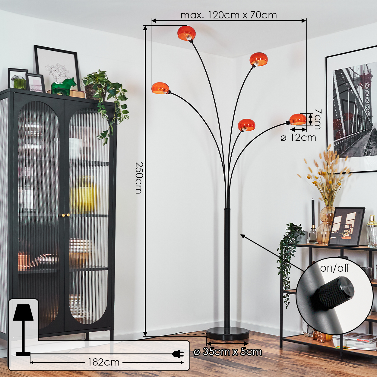 Eine moderne Stehlampe mit orangen Lampenschirmen steht in einem Raum. Ein schwarzer Schrank und Regale mit Dekorationen sind sichtbar.