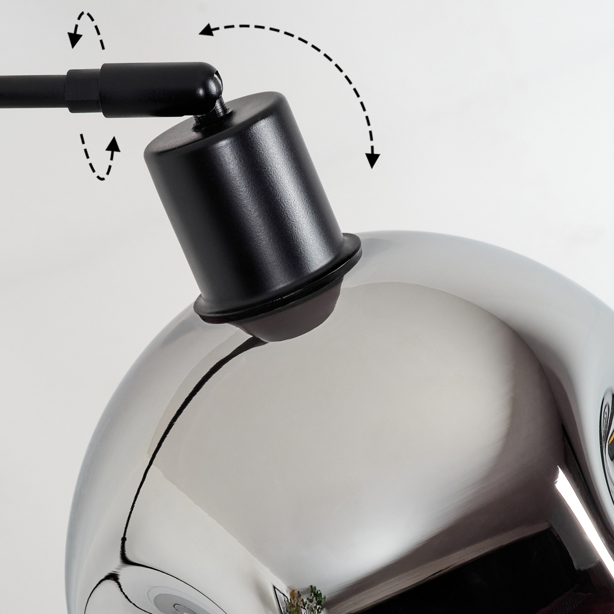 Nahaufnahme einer Chromlampe mit einem schwarzen, verstellbaren Arm und Kopf. Pfeile zeigen mögliche Bewegungen an. Der Hintergrund ist weiß.