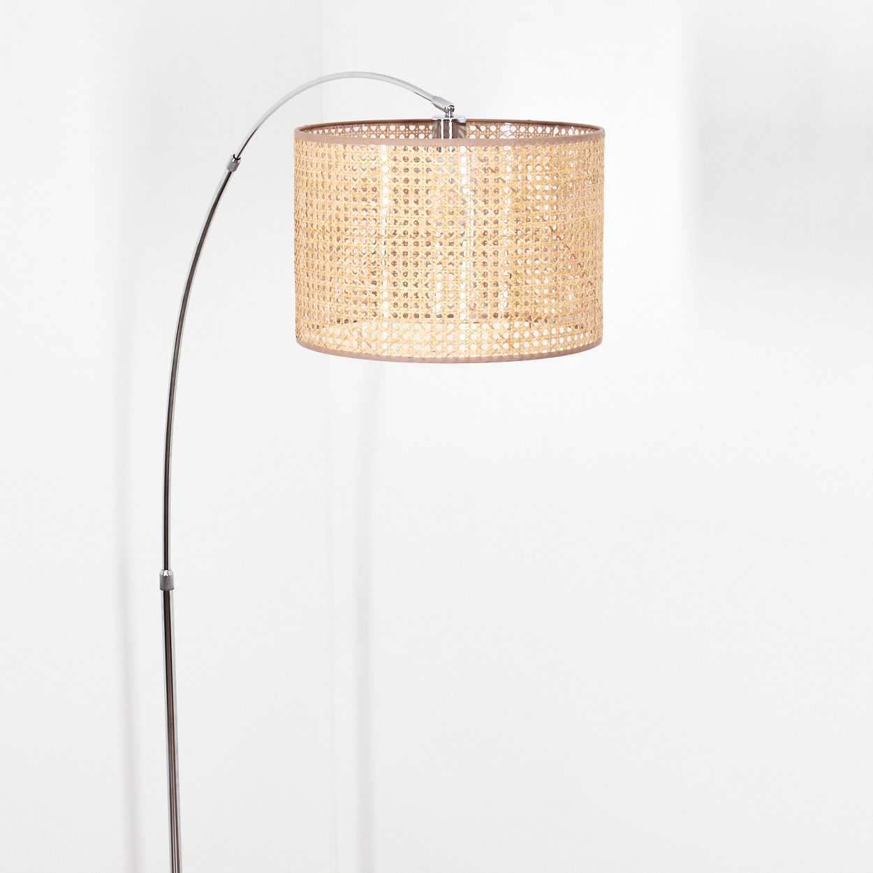Eine moderne Stehlampe mit gewebtem Lampenschirm. Die Lampe hat ein silbernes Metallgestell und einen beigen, zylindrischen Schirm. Der Hintergrund ist weiß.