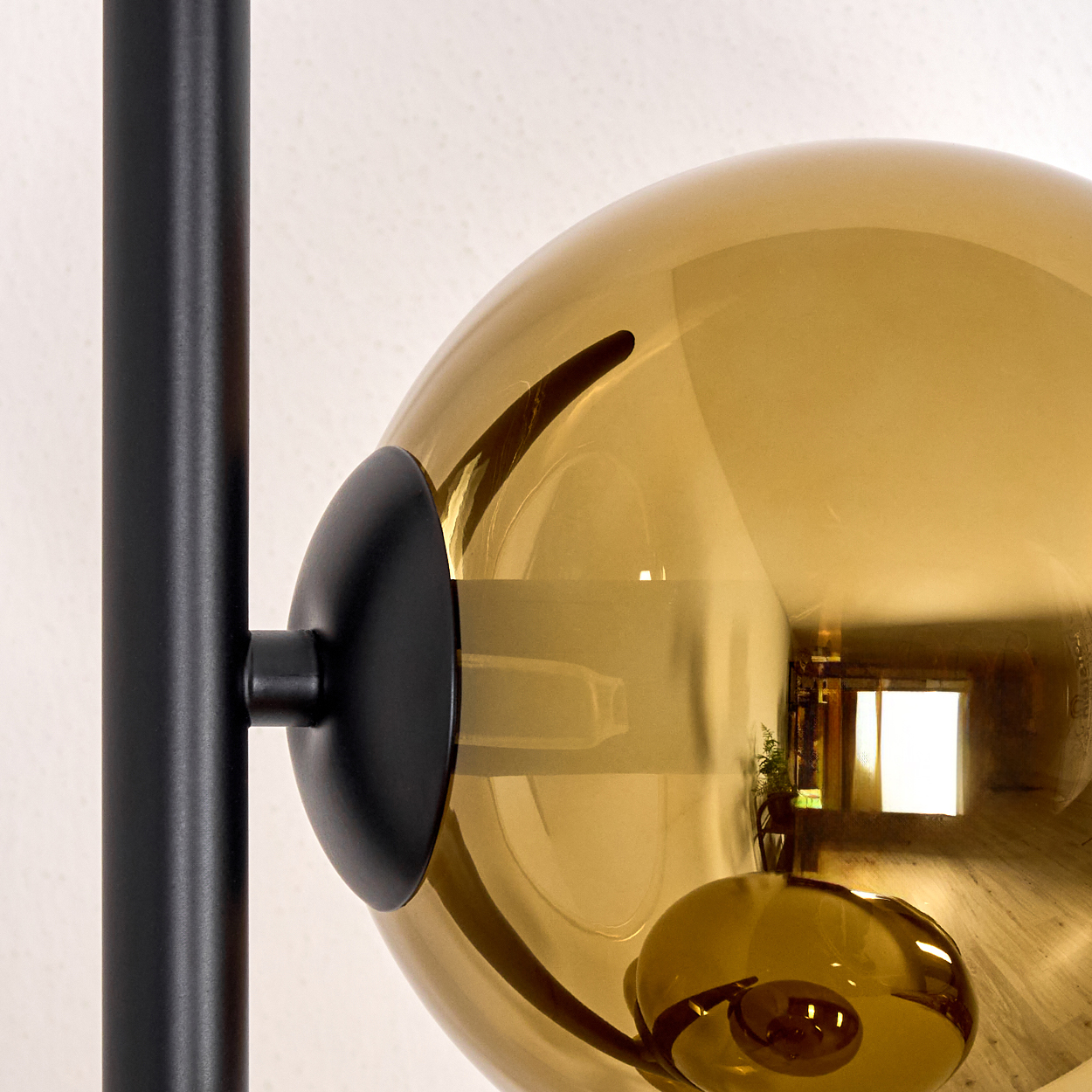 Nahaufnahme einer Lampe. Eine große, bernsteinfarbene Glaskugel ist an einer schwarzen Metallstange befestigt.