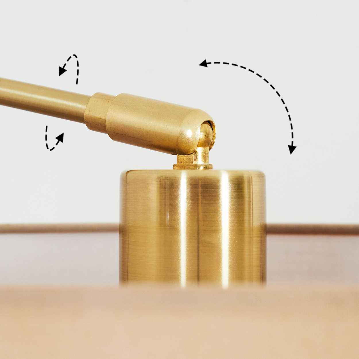 Nahaufnahme eines Messinglampengelenks mit Bewegungspfeilen. Sockel und Arm der Lampe sind golden, vor weißem Hintergrund.