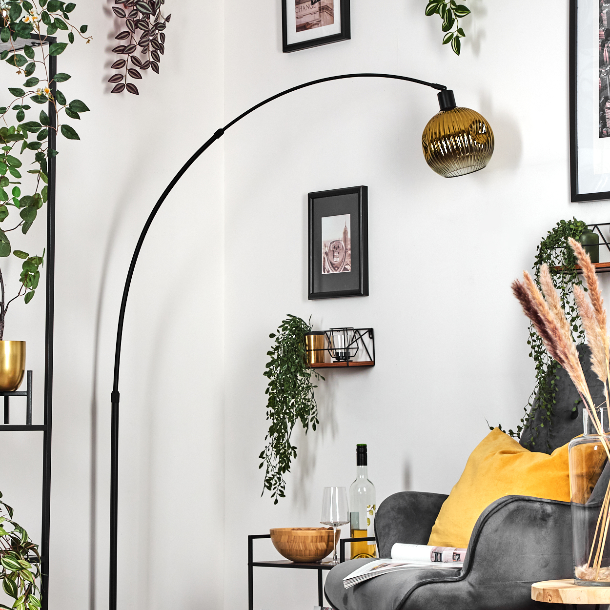 Ein modernes Wohnzimmer mit schwarzer Stehlampe, grauem Sessel mit gelbem Kissen und dekorativen Pflanzen.