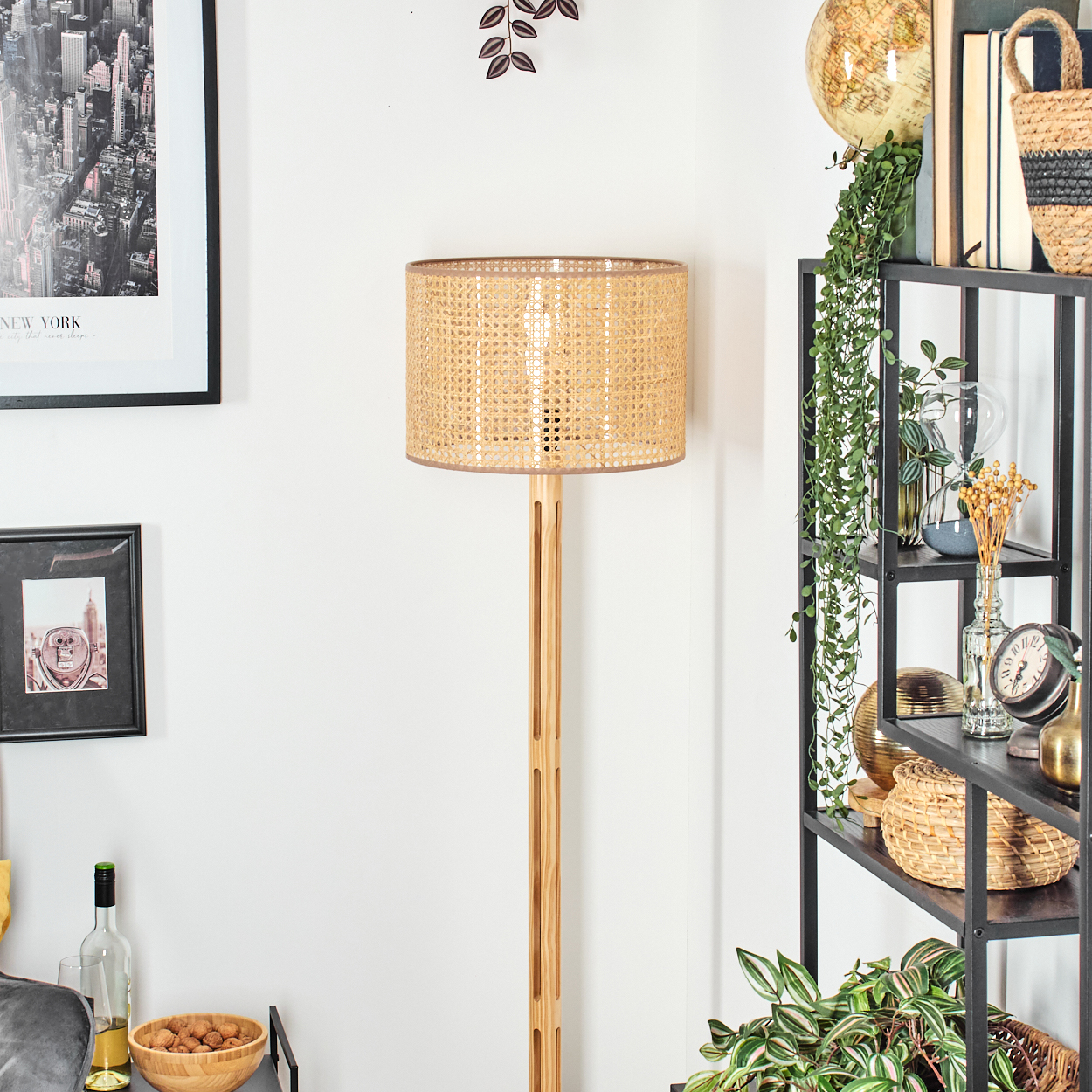 Ein Raum mit einer Holzlampe, einem schwarzen Regal mit Dekorationen und gerahmten Bildern an der Wand. Eine Schale mit Walnüssen steht auf einem Tisch.