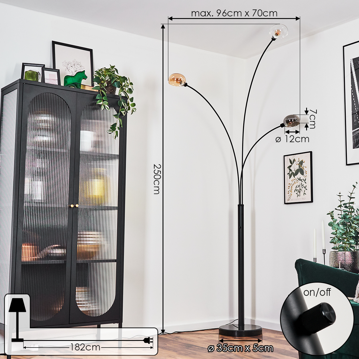 Eine schwarze Stehlampe mit drei Lichtern. Sie befindet sich in einem Raum mit einem schwarzen Schrank und einem grünen Sofa. Maße sind angegeben.