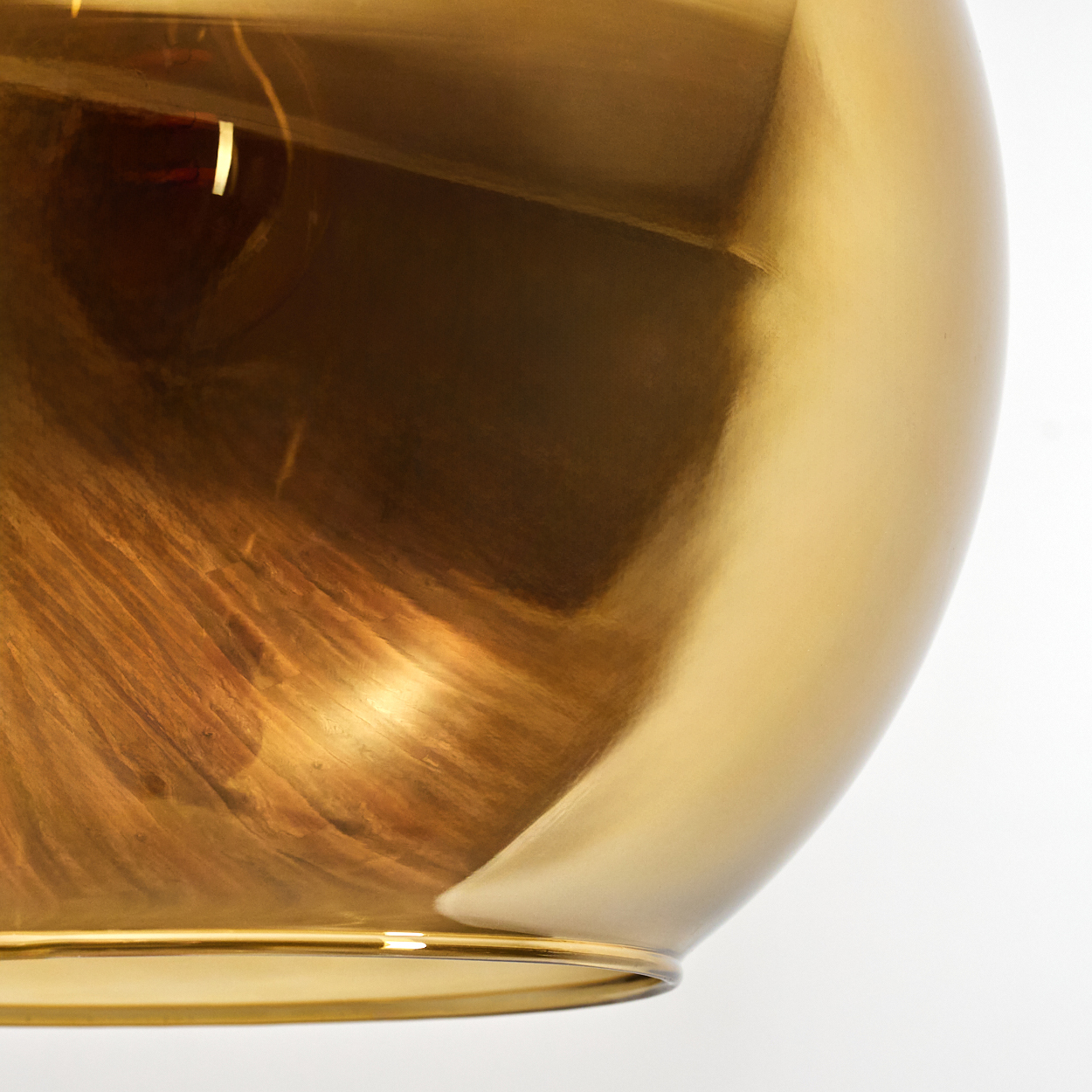 Nahaufnahme eines goldenen, reflektierenden Objekts. Licht spielt auf der Oberfläche und erzeugt Wirbelmuster. Weißer Hintergrund.