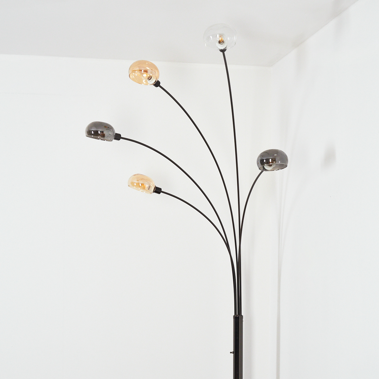 Eine moderne Stehlampe mit fünf gebogenen Armen, die jeweils eine kugelförmige Leuchte halten. Die Lichter wechseln sich ab.
