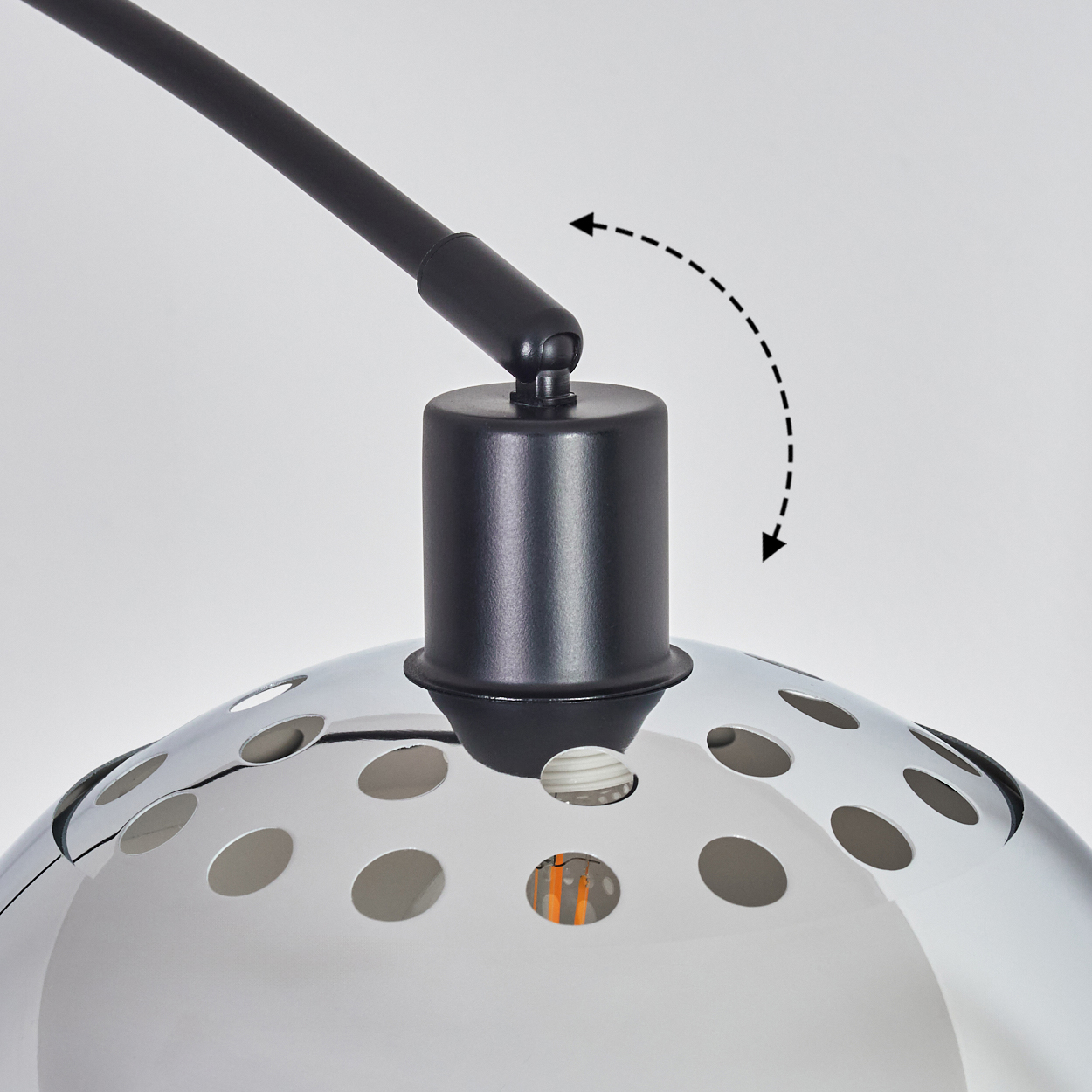 Nahaufnahme einer Lampe. Schwarzer Arm und Sockel, silberner, perforierter Schirm. Ein Pfeil zeigt, dass die Lampe verstellbar ist.