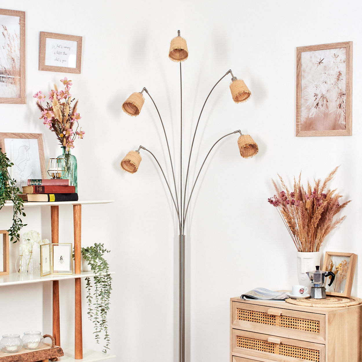 Ein Raum mit Stehlampe, Holzregal mit Büchern und Holzschrank mit Kaffeemaschine.