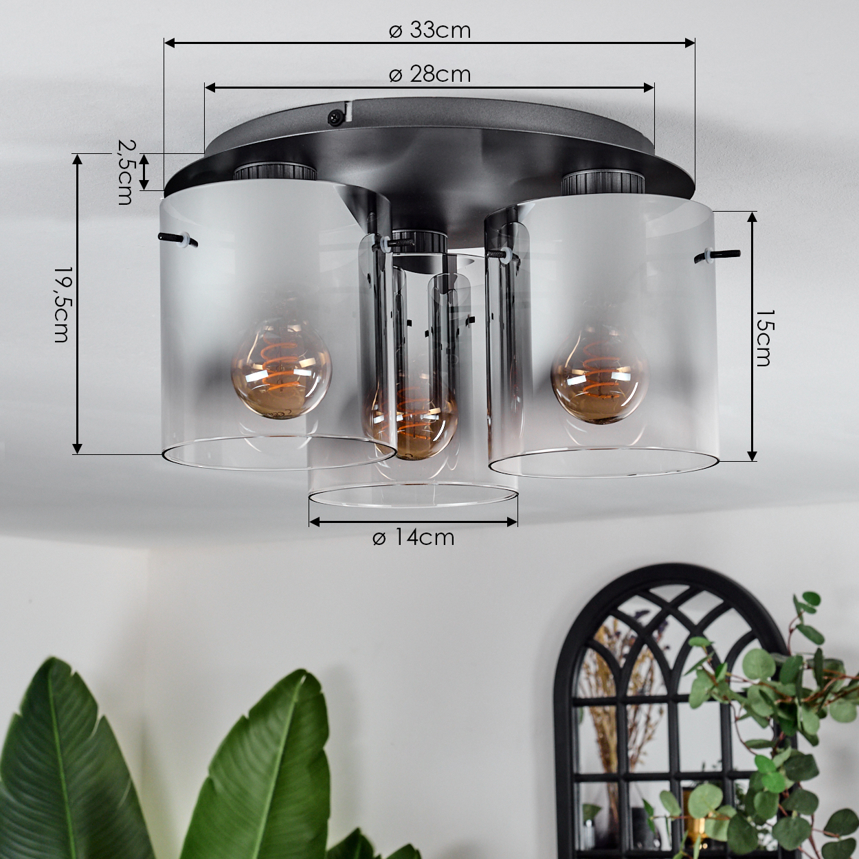 Deckenleuchte mit drei zylindrischen, mattierten Glasschirmen, die warmtonige Glühbirnen beherbergen. Abmessungen sind angegeben. Dekorative Elemente sind im Hintergrund.
