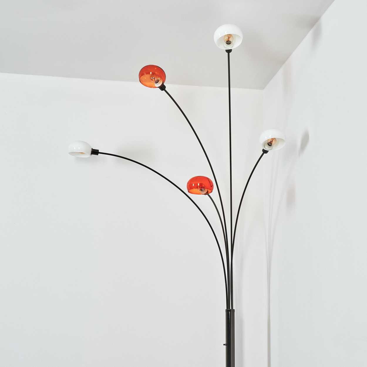 Eine moderne Stehlampe mit fünf Lichtern. Sie hat einen schwarzen Stiel und gebogene Arme, die weiße und orangefarbene Kugeln halten.