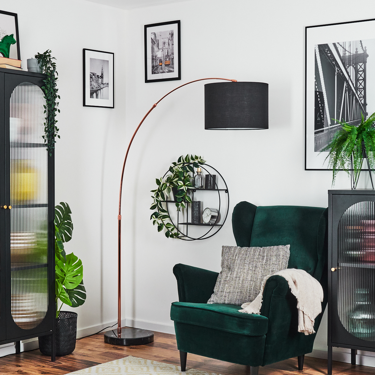 Ein Raum mit grünem Sessel, Stehlampe, schwarzen Schränken, Bildern an der Wand und dekorativen Pflanzen. Gemütliches und stilvolles Interieur.