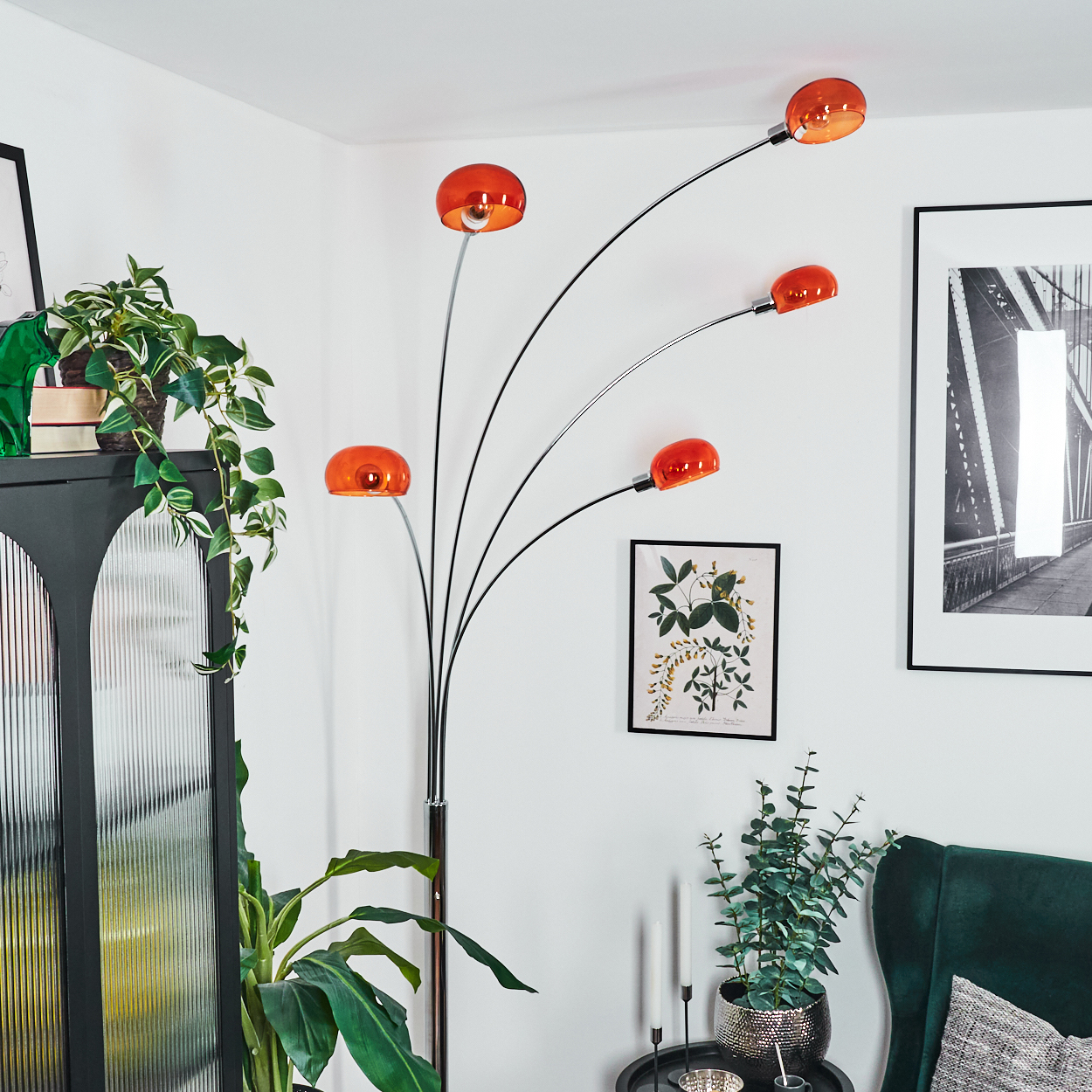 Modernes Wohnzimmer mit einzigartiger orangener Lampe. Pflanzen, Kunstwerke und ein grüner Sessel ergänzen die Einrichtung, vor weißen Wänden.